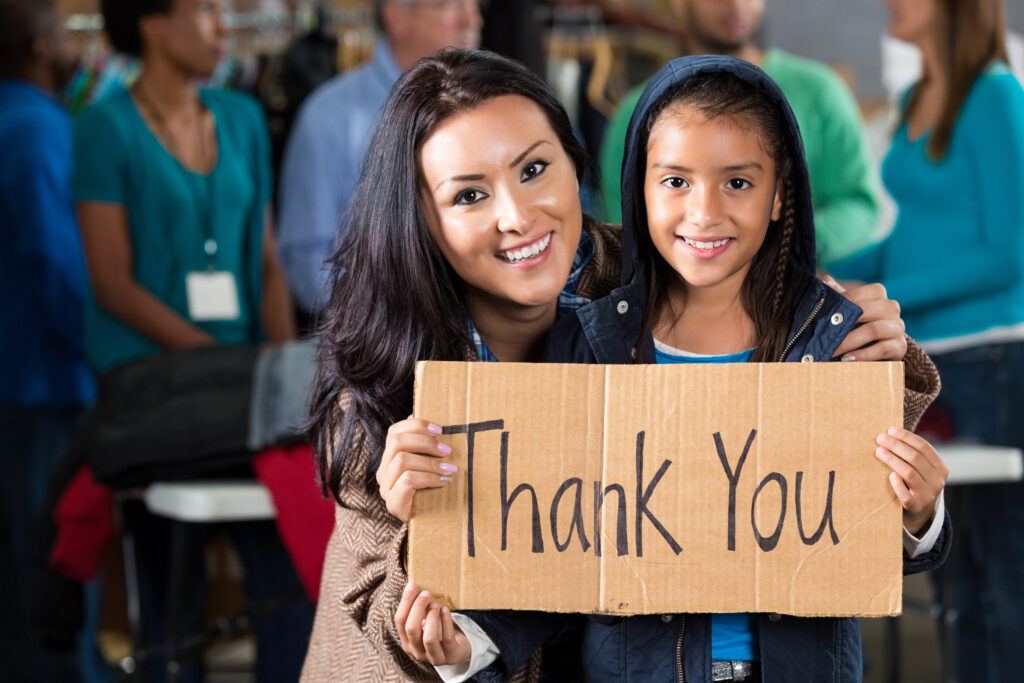 Mom and Child holding a sign that reads "thank you" to the donors of the Winter Wishes Gift Program